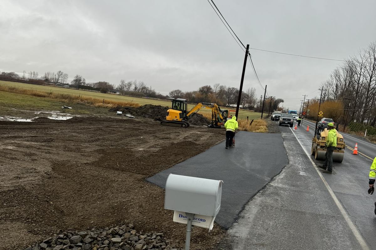 New paved commercial approach with culvert and crew in high-visibility gear