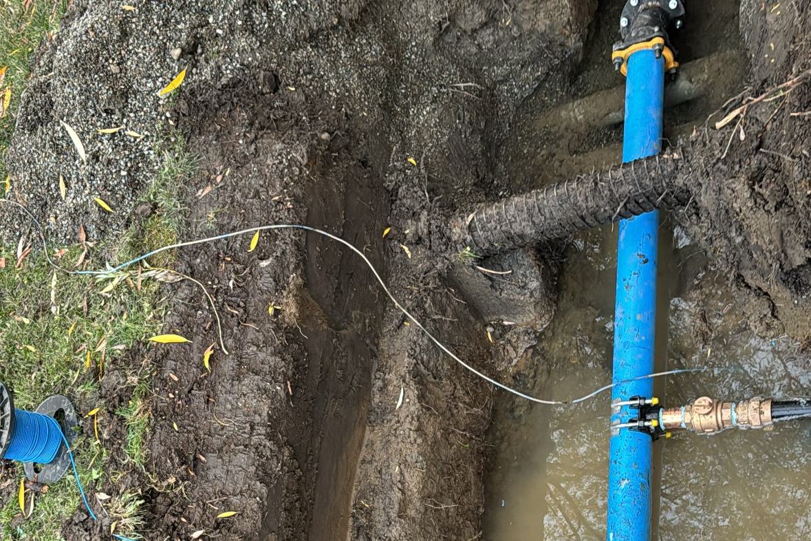 Blue HDPE water main with a tapped service saddle in an open trench