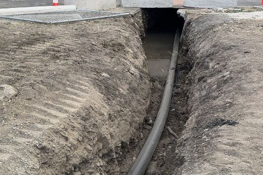 Open trench with service pipe along a residential street
