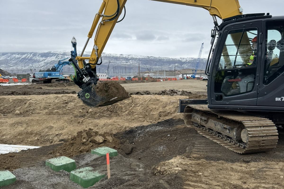 Excavator working near concrete tanks on a large campus site