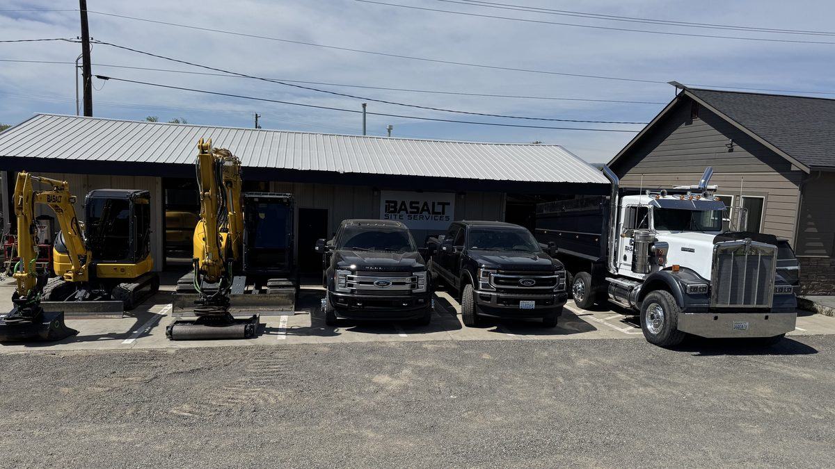 Company shop with equipment and trucks parked outside