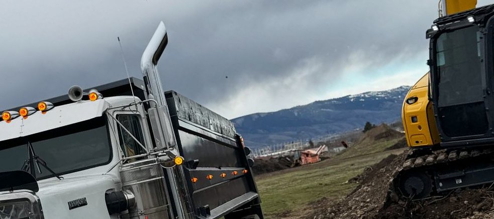 Excavator and Kenworth dump truck working a hillside cut