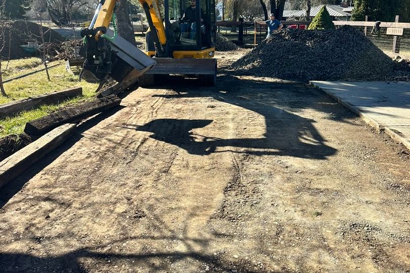 Excavator spreading aggregate on a new gravel driveway