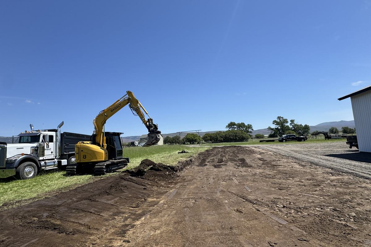 Excavator and dump truck cutting and hauling on an open field