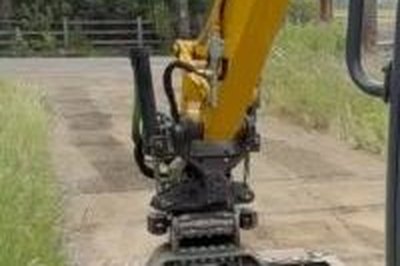 Excavator finishing a gravel shoulder with a grading beam