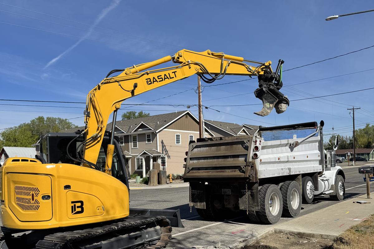 Excavator loading removed concrete and asphalt into a dump truck